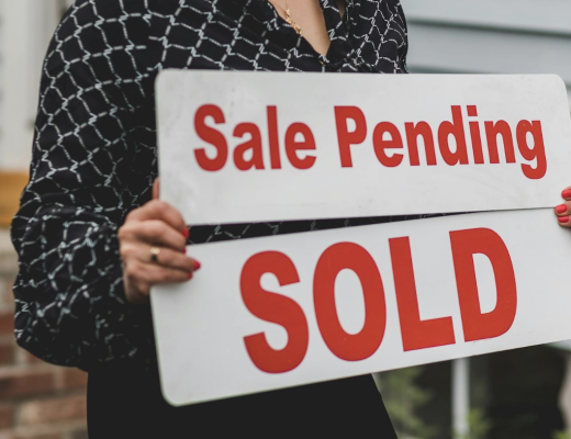 Female Real Estate Agent Holding Sale Pending and Sold Signs